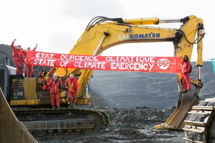Protesters hang banners from a digger inside a coal mine, as part of a direct action against climate change