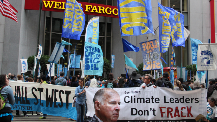 A group of climate activists take action outside a bank