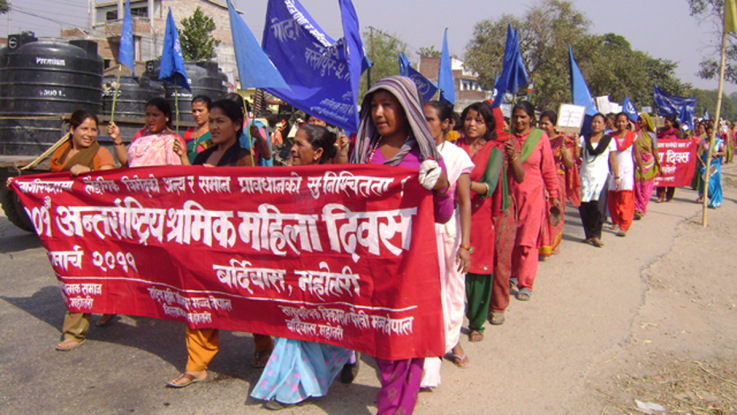 Activists in Nepal marching behind a red banner