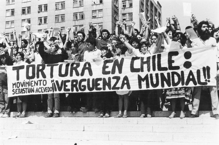 Activists hold a banner condemning torture in Chile