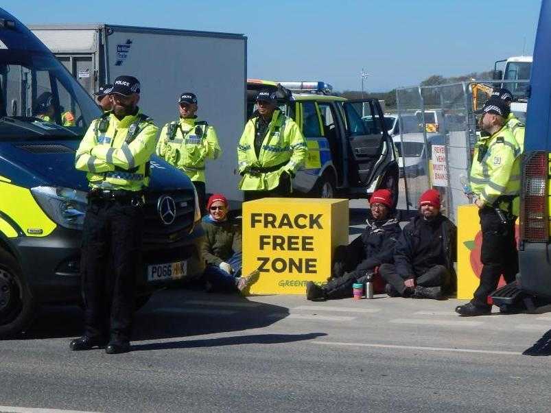Greenpeace activists locked on to a large yellow box reading "Frack Free"
