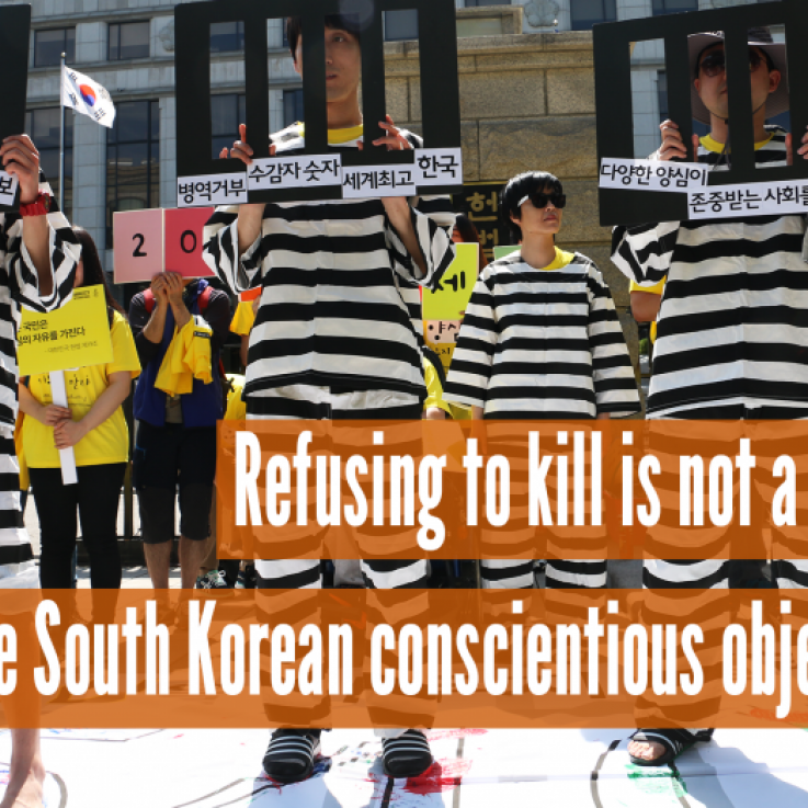 Las personas de pie con carteles que parecen barrotes de la prisión, con el texto "Negarse a matar no es un delito, objetores de conciencia surcoreanos libres"