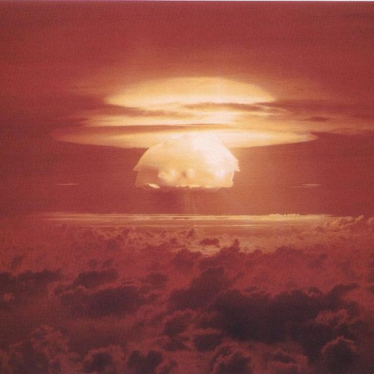 An image of the Castle Bravo nuclear test. A mushroom cloud lights the sky red and yellow.